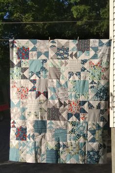 a blue and white quilt hanging from a clothes line