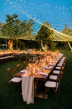 an outdoor dinner setup with white linens and string lights strung over the tables at night