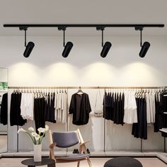 a clothing store with clothes hanging from the ceiling and lights on the wall above it