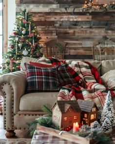 a living room decorated for christmas with plaid and plaid blankets on the couch, candles in the