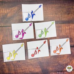 four cards with music notes on them sitting on top of a wooden table next to scissors