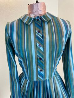 "1960's Blue And Green Stripe Shirt Dress This is such a great shirt dress. The stripes and the careful placement of them make this shirt dress next level attractive. Just check out the pictures and see how the stripes were perfectly utilized to make a regular cut shirt dress into something special. This dress is a button front closure, has her makers tag, which is frayed. Maker is Carol Rodgers Juniors Measurements provided are flat and have been doubled. Bust 34\" Waist 25\" Hips free\" Length Retro Blue Button-up Dress, Striped Fitted Cotton Shirt Dress, Fitted Striped Cotton Shirt Dress, Striped Cotton Shirt Dress With Buttons, Blue Vertical Stripes Dress For Daywear, Fitted Striped Shirt Dress For Daywear, Striped Fitted Collared Dress, Fitted Striped Collared Dress, Fitted Striped Shirt Dress With Buttons