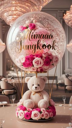 a teddy bear sitting on top of a table next to a large bubble ball filled with flowers