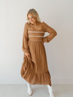 Twirl around in the "Wynn Dress!" This elevated maxi dress is perfect for church or work because of its modest design and fall color! It boasts a soft waffle print fabric, mocha base with ivory rick-rack along the bust, and long balloon sleeves. Easy to pair with boots or heels to complete the look! Detailed Fit: Square neckline maxi dress Cinching at top of shoulder Tie at back of neckline Zipper in the back Waffle pattern throughout skirt Double-lined Overfall Fit: Fitted through bust with a r Modest Midi Dress With Lace Trim, Modest Ruffled Maxi Dress For Fall, Modest Ruffle Maxi Dress For Fall, Fall Maxi Dress With Lace Trim, Maxi Dress With Lace Trim For Fall, Lace Trim Maxi Dress For Fall, Modest Brown Midi Dress For Spring, Brown Modest Midi Dress For Spring, Modest Fitted Maxi Dress With Lace Trim