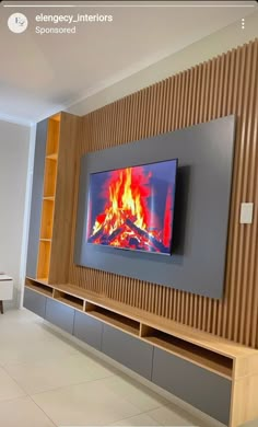 a large television mounted to the side of a wall with a fire burning in it