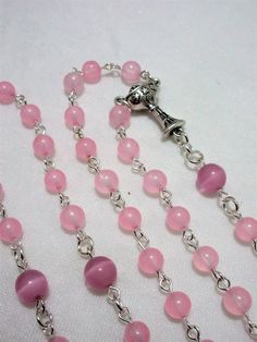 This pink First Communion rosary for girls is made with 6mm pale pink agate rounds and 8mm matte pink cat's eye beads. It measures about 27 inches around the body and has a 5 inch cross drop. The crucifix and the chalice are Italian made oxidized silver. I hand turned the silver plated wires. This rosary will be slipped into a velvet bag and shipped in a bubble mailer. Pink Rosary With Round Beads For First Communion, Pink Rosary For First Communion, Pink Rosary With 8mm Round Beads, Handmade Pink Rosary With Round Beads, Pink Beaded Rosary With Round Beads, Pink Beaded Rosary, Catholic Communion, Catholic Rosary, Matte Pink