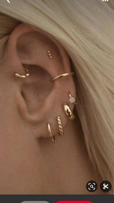 an ear with three different types of piercings on it, and one is gold