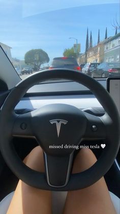 a woman sitting in the driver's seat of a car with her feet on the steering wheel