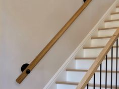 a wooden hand rail on the side of a stair case next to a banister