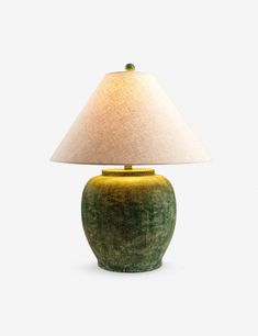 a green table lamp with a white shade on the base and a light bulb attached to it