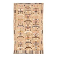 a beige rug with multicolored designs on the front and back, hanging from a white wall