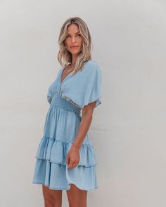 This Sylvie Smock Tiered Mini Dress in Chambray is made of 100% Tencel fabric for a soft and lightweight feel! With a dropped shoulder, smocked waist, and tiered mini length, this dress is both comfortable and stylish. Perfect for any occasion, it is easy to dress up or down. Pair with knee high boots, simple gold jewelry, and a cute little clutch for casual chic fall outfit! Chic Smocked Dress For Brunch, Summer Daywear Dresses With Tiered Skirt, Chic Tiered Smocked Dress, Smocked Tiered Dress For Brunch, Chic Smock Dress For Brunch, Flowy Smocked Mini Dress, Chic Smocked Tiered Dresses, Smocked Bodice Tiered Skirt Dress For Brunch, Sundress Tiered Dress With Smocked Back For Brunch