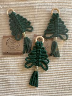 two green crocheted christmas tree ornaments on a white blanket with a tag attached to them