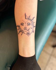 a woman's arm with a sun tattoo on her left leg and a flower in the middle