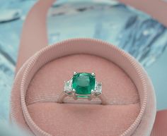 This Elegant Platinum three stone ring has a Natural Cushion Cut Colombian Emerald from the Top Muzo Mine with a GIA Certificate. The side stones are Natural Brilliant Cut Trapezoid Pair of Matching Diamonds. GIA#5202111099 3.34 Carat Cushion Modified 9.64x8.93x5.64 with moderate F2 clarity enchancement. 2 Matching Trapezoid Brilliant Cut Diamonds weigh 0.71 carats total weight and are graded G in color and SI1 to SI2 in clarity. Platinum weight is 5.14 DWT. Ring can be sized. Luxury Dazzling Emerald Ring With Accent Stones, Luxury Princess Cut Emerald Ring With Accent Stones, Luxury Three Stone Emerald Ring Gift, Three Stone Cushion Cut Ring, Fine Jewelry Emerald Platinum Ring With Three Stones, Platinum Three Stone Emerald Ring, Three-stone Emerald Diamond Ring As Gift, Three Stone Emerald And Diamond Ring For Gift, Luxury Three Stone Emerald Wedding Ring