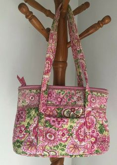 a pink and green floral purse hanging on a coat rack