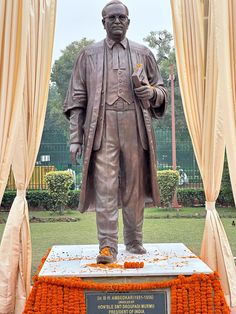 a statue of a man standing in front of a window with orange flowers around it