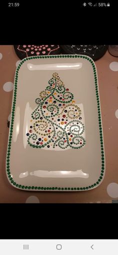 a white plate with a christmas tree design on the front and green trim around the edges