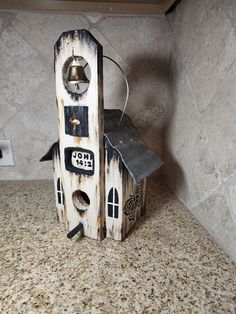 a birdhouse made out of wood and metal with a bell on the top that is attached to it