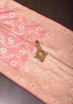 an old pink and gold cloth with a butterfly on the center, sitting on a wooden floor