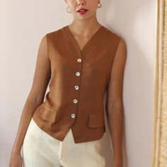 Vintage handmade statement vest blouse in a chocolate brown shade. V neckline and delicate flower-shaped mother of pearl button up fastening. Tailored fit with a slightly cinched waistline to hug beautiful your figure. Decorative front pockets. Lightweight and soft against the body.  You can wear it both as a blouse or layered with a top underneath. It's the perfect garment for a standout look from day to night! BRAND: No tag, handmade MATERIAL: No tag, estimated as viscose **CONDITION: Excellen Elegant Brown V-neck Blouse, Brown V-neck Vest For Workwear, Fitted V-neck Brown Blouse, Brown V-neck Vest For Work, Brown Workwear Tops With Button Closure, Brown Button Closure Tops For Work, Brown Tops With Button Closure For Work, Brown V-neck Blouse With Button Closure, Brown Buttoned Blouse For Work