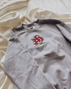 "Mushroom House Embroidered Sweatshirt! Embroidered on a cotton/polyester blend crewneck sweatshirt! This design is simple and minimalistic perfect for the cottage core look! -Embroidery design measures 5\" x 4\" -See product pictures for shirt sizing chart. -All sweatshirts are handmade on an embroidery machine so there may be slight differences, but we only sell the sweatshirts that meet our high-quality standards. -To maintain the quality of your sweatshirt and the embroidery design make sure Cotton Fall Sweatshirt With Mushroom Print, Cotton Sweatshirt With Mushroom Print For Fall, Casual Fall Sweatshirt With Mushroom Print, Casual Mushroom Print Sweatshirt For Fall, Cotton Crew Neck Sweatshirt With Mushroom Print, Casual Crew Neck Sweatshirt With Mushroom Print, Casual Long Sleeve Top With Mushroom Design, Fall Mushroom Print Crew Neck Sweatshirt, Winter Cotton Tops With Mushroom Print