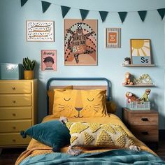 a child's bedroom with blue walls, yellow bedding and pictures on the wall