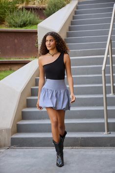 a young woman is walking down the stairs wearing boots and a black top with a blue ruffle skirt