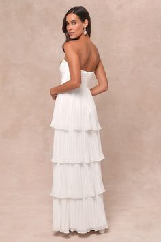 a woman wearing a white dress with tiered layers on the bottom and one shoulder