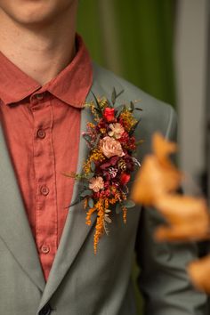 a man in a gray suit with a red shirt and flower boutonniere