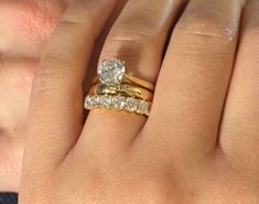 a woman's hand with two gold rings and one diamond ring on her finger