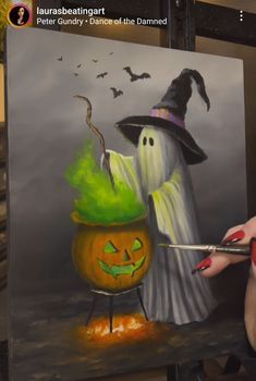 a woman is painting a halloween scene with pumpkins and witch hats on her face