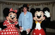 a man standing next to two mickey mouses