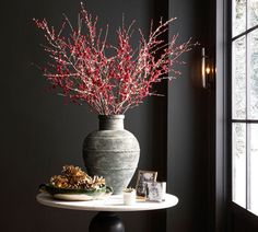 a vase filled with red flowers sitting on top of a table next to a window