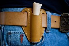 a person wearing jeans with a tool in their back pocket that has a leather belt on it