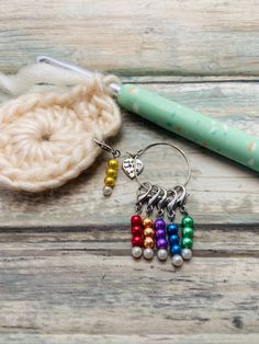 a crochet hook with beads on it next to a pen and knitting needle