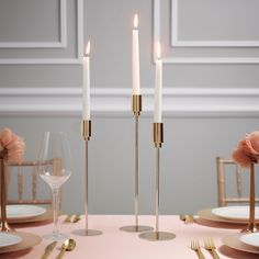 three candles are lit on a table with plates and utensils