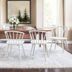 three white chairs sitting on top of a rug in front of a wooden coffee table