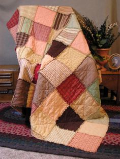 a quilted blanket sitting on top of a rug next to a table with a potted plant