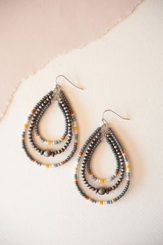 Introducing the Brodie Beaded Teardrop Dangle Earrings, a celebration of vibrant colors and artistic design. These earrings feature teardrop-shaped dangles adorned with a captivating array of multicolored beads, creating a bold and eye-catching look. Perfect for adding a playful and eclectic touch to your outfit, they effortlessly complement both casual and festive attire with their unique charm and dynamic hues. The Brodie Beaded Teardrop Dangle Earrings are ideal for those who love to make a s Gift Teardrop Earrings With Colorful Beads, Dangle Teardrop Earrings With Tiny Beads, Colorful Beaded Dangle Teardrop Earrings, Bohemian Dangle Teardrop Earrings With Faceted Beads, Silver Beaded Teardrop Earrings, Bohemian Teardrop Dangle Earrings With Colorful Beads, Bohemian Colorful Beaded Teardrop Earrings, Multicolor Beaded Teardrop Dangle Earrings, Multicolor Beaded Teardrop Earrings