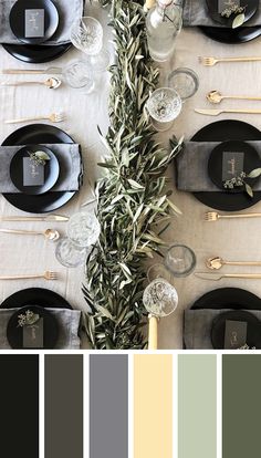 the table is set with black and white plates, silverware, olive branches, and candlesticks