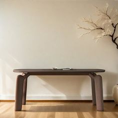 a wooden table sitting on top of a hard wood floor next to a white wall