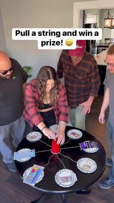 a group of people standing around a table with cards on it and one person holding a red object