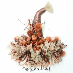 an orange and white fall wreath with pumpkins, feathers and burlocks on it