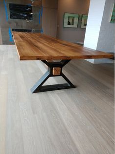 a wooden table sitting on top of a hard wood floor next to a white wall