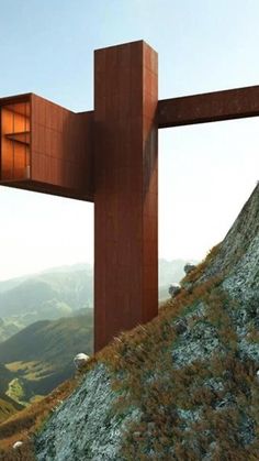 a wooden structure sitting on top of a hill next to a lush green hillside covered in grass