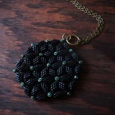 a black and green beaded necklace on a wooden table with a chain attached to it