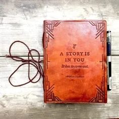 a brown leather book with writing on the front cover and cord attached to it, sitting on a wooden surface