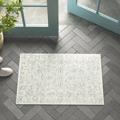 a white rug sitting on top of a wooden floor next to a potted plant