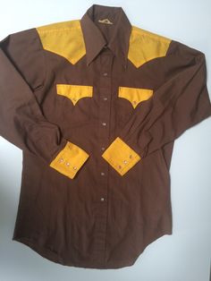 Vintage Western Men's color block shirt-chocolate brown w/nice bright golden yellow. Size 15 1/2 neck x 34" sleeve. Would say this is a size Medium, but slightly fitted, very flattering Permanent press with mother of pearl snap buttons. Triple snap cuffs. Other than a little grin through at the collar tips(see close up),and slight fraying at shirt tail  this is in excellent condition (fixable) Payment - All major credit cards and Paypal  Shipping - If you don't find your country listed as a shipping option, please send me an email and I will do my best to find shipping costs for your country. Most packages will be sent by USPS regular mail and do not automatically come with insurance. If you want your item insured please advise me before ordering.  Refunds and Exchanges - Sorry, but not in Fitted Yellow Shirt For Fall, Yellow Fitted Shirt For Fall, Retro Brown Cotton Shirt, Fitted Cotton Shirt With Color Block, Fitted Cotton Color Block Shirt, Brown Fitted Shirt For Fall, Fitted Brown Shirt For Fall, Fitted Brown Collared Shirt, Fitted Collared Brown Shirt